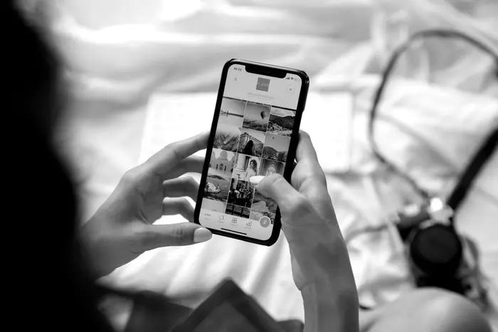 Close-up of hands holding a smartphone and scrolling through an image feed