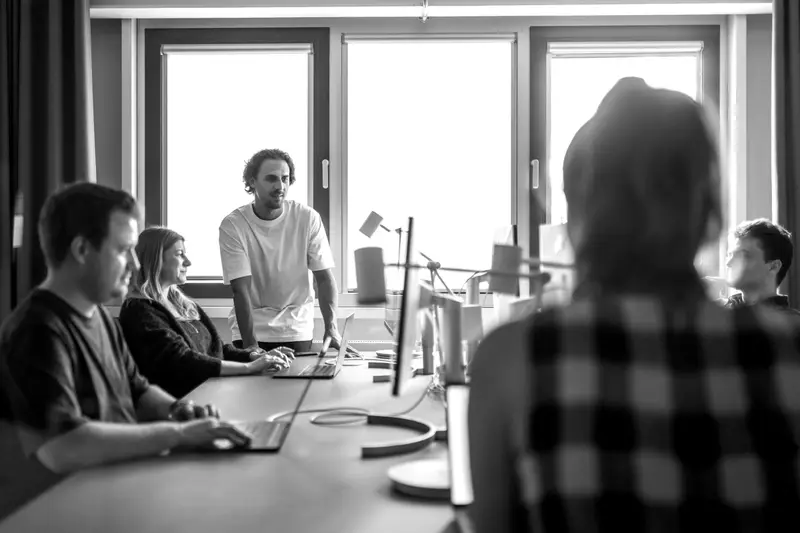 People working at computers around a long desk in an open office